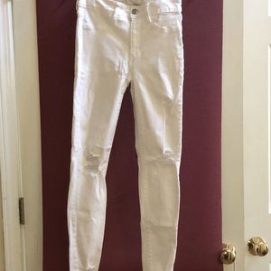 White distressed denim jeans with silver buttons.